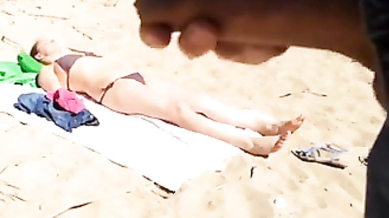 Jerking off as a bikini woman lies on the beach