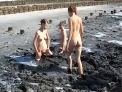 Young ladies coat their bodies in dark mud