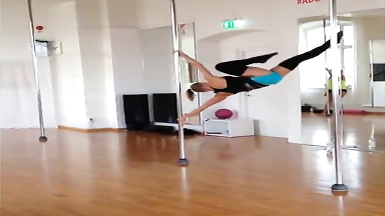 Stunningly fit girl swings around the pole