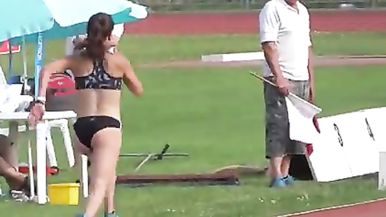 Athletic girl runs around the track in tight clothes