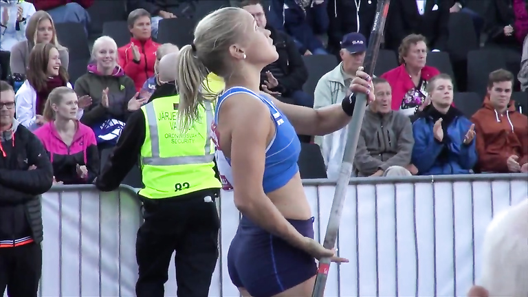 Hot blonde pole vaulter competes at a packed stadium