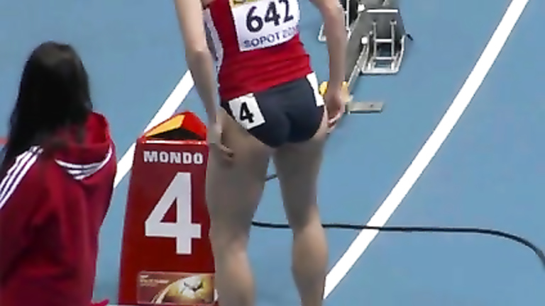 Athletic woman runs around the track in a flimsy outfit