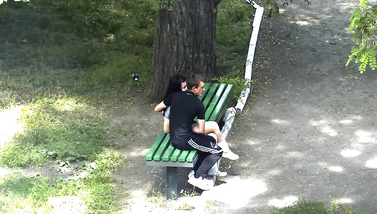 Russian lovers kiss and caress each other in the city park voyeurstyle