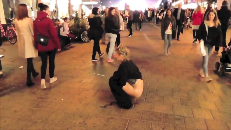 Brave blonde urinates on the middle of the crowded street!