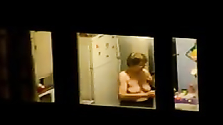 Large-breasted granny changes her clothes by the window