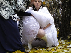 Bride struggles with her wedding dress as she pees in the woods