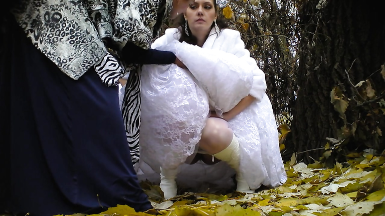 Bride struggles with her wedding dress as she pees in the woods