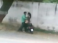 Pakistani couple bangs on a moped by the side of the road