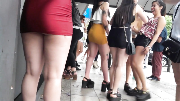 Long-haired coed girl is wearing a red miniskirt in public voyeurstyle