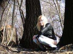 Irresistible girl holds onto jeans while piddling in the city park