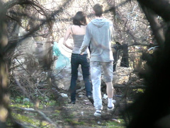 Caring boyfriend covers up girl peeing in the shrub