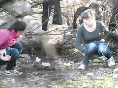 Two college girls squat and pee in the woods