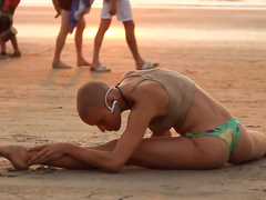 Bald beauty doing yoga by the sea