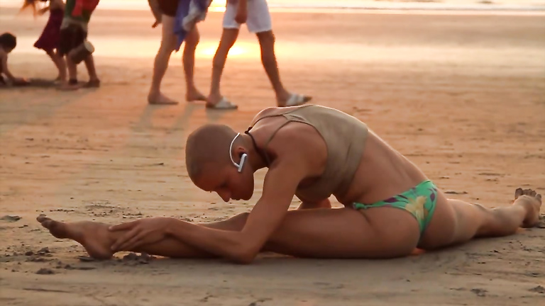 Bald beauty doing yoga by the sea