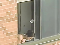 Topless woman looks out her window
