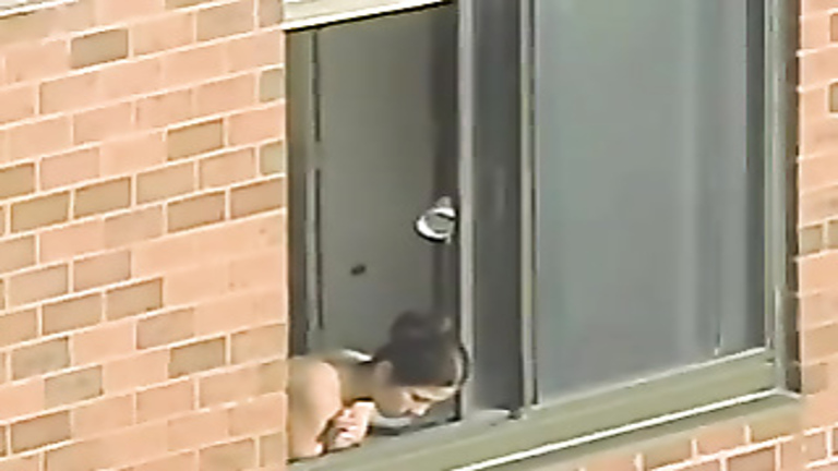 Topless woman looks out her window voyeurstyle pic photo